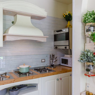 Ispirazione per una cucina stile shabby con ante con bugna sagomata, ante bianche, top in legno e paraspruzzi con lastra di vetro