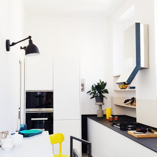 Idee per una piccola cucina contemporanea con ante lisce, ante bianche, elettrodomestici da incasso, penisola, pavimento grigio e top nero
