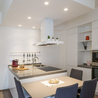 Immagine di una cucina contemporanea con ante lisce, ante bianche, penisola, lavello sottopiano, paraspruzzi bianco, elettrodomestici in acciaio inossidabile, parquet chiaro, pavimento beige e top grigio
