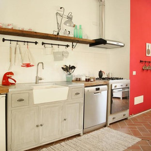 Immagine di una cucina lineare country con elettrodomestici in acciaio inossidabile, lavello stile country, ante con riquadro incassato, ante grigie, top in legno, paraspruzzi bianco e pavimento marrone