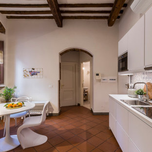 Foto di una cucina mediterranea di medie dimensioni con lavello da incasso, ante lisce, ante bianche, paraspruzzi multicolore, paraspruzzi in gres porcellanato, elettrodomestici in acciaio inossidabile, pavimento in terracotta, nessuna isola, pavimento rosso, top bianco e travi a vista