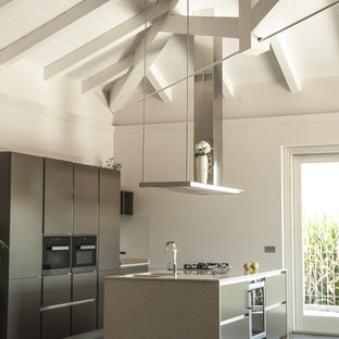Immagine di una cucina contemporanea con lavello sottopiano, ante lisce, elettrodomestici neri, isola, pavimento grigio, ante grigie, pavimento in cemento e top beige