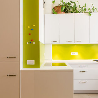 Foto di una cucina a L design con lavello a doppia vasca, ante lisce, ante bianche, paraspruzzi verde, nessuna isola, top bianco e pavimento beige