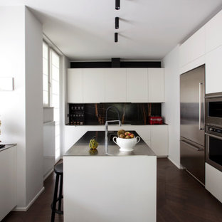 Idee per una cucina minimal con lavello sottopiano, ante lisce, ante bianche, paraspruzzi nero, elettrodomestici in acciaio inossidabile, parquet scuro, pavimento marrone e top nero
