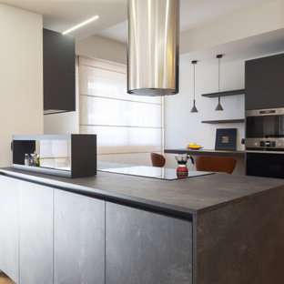 Immagine di una cucina minimal di medie dimensioni con lavello da incasso, ante lisce, ante nere, top in laminato, elettrodomestici in acciaio inossidabile, parquet chiaro e top nero