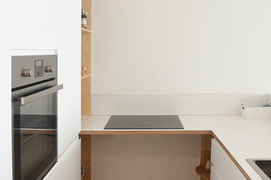 ミラノにある低価格の小さな北欧スタイルのおしゃれなキッチン (シングルシンク、フラットパネル扉のキャビネット、白いキャビネット、ラミネートカウンター、白いキッチンパネル、木材のキッチンパネル、シルバーの調理設備、淡色無垢フローリング、アイランドなし) の写真