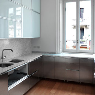 Foto di una cucina a L minimal di medie dimensioni con lavello sottopiano, ante lisce, ante in acciaio inossidabile, paraspruzzi bianco, pavimento in legno massello medio, nessuna isola, pavimento marrone e top bianco