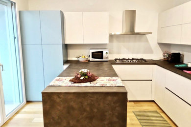 Esempio di una grande cucina minimalista con lavello da incasso, top in laminato, elettrodomestici in acciaio inossidabile, parquet chiaro, penisola e top nero