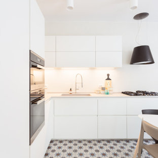 Foto di una grande cucina a L scandinava chiusa con top in superficie solida, paraspruzzi bianco, pavimento multicolore, lavello sottopiano, ante lisce, ante bianche e elettrodomestici in acciaio inossidabile