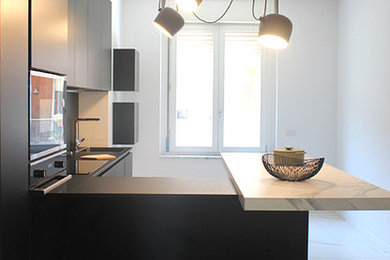 Idee per una cucina lineare moderna chiusa e di medie dimensioni con lavello a vasca singola, ante lisce, ante nere, top in superficie solida, paraspruzzi nero, elettrodomestici neri, penisola e top nero