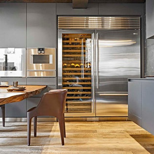 Ispirazione per una cucina minimal con ante lisce, ante grigie, paraspruzzi grigio, elettrodomestici in acciaio inossidabile e parquet chiaro