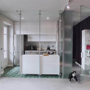 This is an example of a mid-sized contemporary galley separate kitchen in Turin with a single-bowl sink, flat-panel cabinets, white cabinets, laminate benchtops, white splashback, porcelain splashback, stainless steel appliances, cement tiles, with island and green floor.