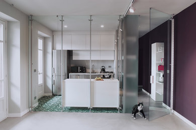 This is an example of a medium sized contemporary galley enclosed kitchen in Turin with a single-bowl sink, flat-panel cabinets, white cabinets, laminate countertops, white splashback, porcelain splashback, stainless steel appliances, cement flooring, an island and green floors.