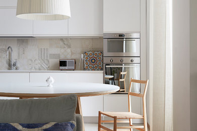 This is an example of a medium sized contemporary single-wall open plan kitchen in Milan with an integrated sink, beaded cabinets, white cabinets, stainless steel appliances, light hardwood flooring, an island and brown floors.