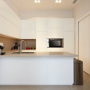 Esempio di una cucina ad U minimalista con ante lisce, ante bianche, lavello a vasca singola, paraspruzzi grigio, elettrodomestici da incasso, penisola, pavimento grigio e top grigio