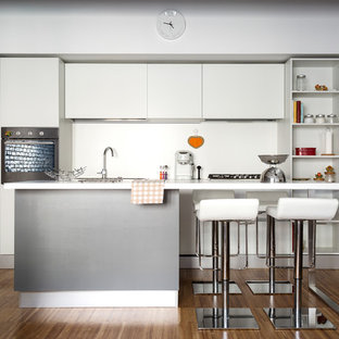 Immagine di una cucina lineare moderna di medie dimensioni con ante lisce, ante bianche, paraspruzzi bianco, pavimento in legno massello medio, isola, pavimento marrone e lavello sottopiano