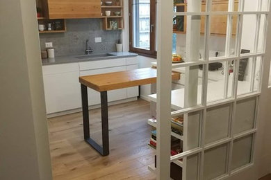 Ispirazione per una cucina design di medie dimensioni con lavello sottopiano, ante lisce, ante in legno chiaro, top in superficie solida, paraspruzzi grigio, paraspruzzi in gres porcellanato, elettrodomestici in acciaio inossidabile, parquet chiaro e top grigio