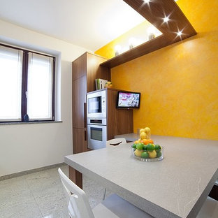 This is an example of a large modern single-wall separate kitchen in Milan with an integrated sink, flat-panel cabinets, dark wood cabinets, solid surface benchtops, grey splashback, stainless steel appliances and porcelain floors.