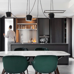 Immagine di una cucina design di medie dimensioni con top in laminato, pavimento in cemento, pavimento grigio, top nero, ante lisce, ante nere e paraspruzzi a effetto metallico