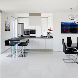 Immagine di una grande cucina abitabile contemporanea con pavimento in gres porcellanato, pavimento bianco, ante lisce, ante bianche, elettrodomestici in acciaio inossidabile, penisola e top nero