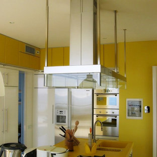 Photo of a large modern separate kitchen in Other with an integrated sink, flat-panel cabinets, white cabinets, solid surface benchtops, stainless steel appliances, ceramic floors, with island, yellow floor and yellow benchtop.