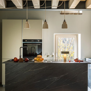 Ispirazione per una cucina rustica di medie dimensioni con lavello da incasso, ante lisce, ante bianche, elettrodomestici neri e top grigio