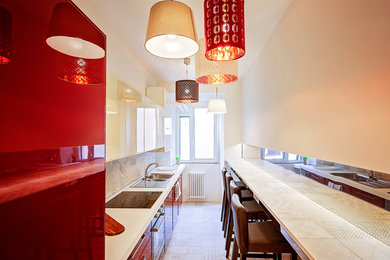 Foto di una piccola cucina lineare moderna chiusa con lavello da incasso, ante lisce, ante rosse, paraspruzzi con piastrelle in ceramica, elettrodomestici neri, pavimento in cementine e pavimento beige