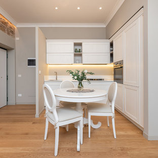 Ispirazione per una cucina chic con lavello a vasca singola, ante con riquadro incassato, ante bianche, elettrodomestici in acciaio inossidabile, parquet chiaro, nessuna isola, pavimento beige, top bianco e paraspruzzi bianco