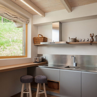 Idee per una cucina lineare moderna con lavello integrato, ante lisce, ante grigie, top in acciaio inossidabile, pavimento in legno massello medio, nessuna isola, paraspruzzi a effetto metallico, paraspruzzi con piastrelle di metallo, elettrodomestici in acciaio inossidabile, pavimento marrone e top grigio