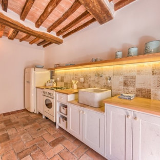 Idee per una piccola cucina lineare mediterranea chiusa con lavello stile country, ante in stile shaker, ante bianche, top in legno, paraspruzzi beige, paraspruzzi con piastrelle in ceramica, pavimento in terracotta e nessuna isola