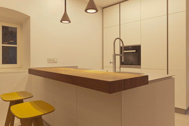 Kleine Moderne Küche mit Unterbauwaschbecken, weißen Schränken, Mineralwerkstoff-Arbeitsplatte, schwarzen Elektrogeräten und grauer Arbeitsplatte in Sonstige
