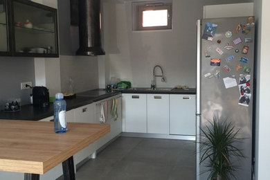 Immagine di una cucina design con ante bianche, paraspruzzi bianco, paraspruzzi con piastrelle in ceramica, pavimento in gres porcellanato, penisola e pavimento grigio