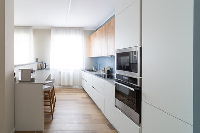 Immagine di una cucina scandinava di medie dimensioni con lavello a doppia vasca, ante bianche, paraspruzzi blu, elettrodomestici neri, pavimento in gres porcellanato e top grigio