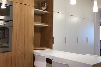 Idee per una cucina contemporanea di medie dimensioni con lavello integrato, ante lisce, ante in legno chiaro, top in superficie solida, elettrodomestici neri, pavimento in gres porcellanato e top bianco