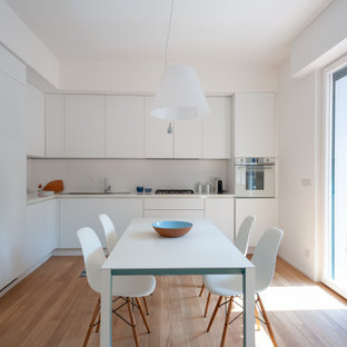 Esempio di una cucina contemporanea con lavello da incasso, ante lisce, ante bianche, paraspruzzi bianco, elettrodomestici da incasso, pavimento in legno massello medio, nessuna isola, pavimento marrone e top bianco