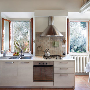 Ispirazione per una cucina country di medie dimensioni con ante lisce, paraspruzzi con piastrelle in ceramica, elettrodomestici in acciaio inossidabile, pavimento in terracotta, nessuna isola, top bianco, lavello a doppia vasca, ante in legno chiaro, paraspruzzi marrone e pavimento marrone