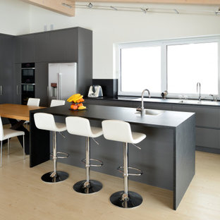Idee per un grande cucina con isola centrale contemporaneo con ante lisce, ante grigie, top in granito, paraspruzzi nero, paraspruzzi in granito, top nero, travi a vista, lavello a vasca singola e pavimento beige