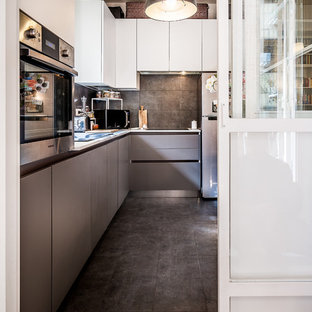 Immagine di una grande cucina a L contemporanea chiusa con ante lisce, ante grigie, pavimento nero, paraspruzzi nero, elettrodomestici in acciaio inossidabile e top grigio