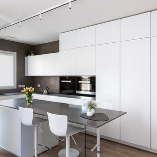 Esempio di una cucina moderna di medie dimensioni con lavello a doppia vasca, ante lisce, ante bianche, top in quarzo composito, elettrodomestici neri, top grigio, pavimento in legno massello medio e pavimento marrone