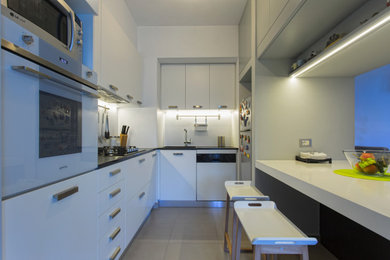 Idee per una piccola cucina contemporanea con lavello integrato, ante a filo, ante bianche, elettrodomestici bianchi, pavimento beige e top grigio