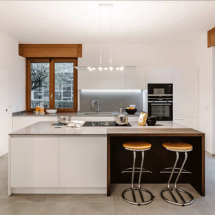 Idee per una grande cucina design con lavello sottopiano, ante lisce, ante bianche, paraspruzzi grigio, elettrodomestici da incasso, pavimento grigio e top grigio