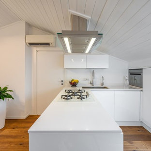 Idee per una cucina nordica con lavello sottopiano, ante lisce, ante bianche, paraspruzzi bianco, pavimento in legno massello medio, penisola e top bianco