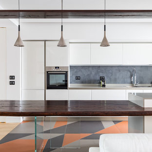Foto di una cucina parallela minimal con lavello a doppia vasca, ante lisce, ante bianche, paraspruzzi grigio, penisola, pavimento multicolore e top grigio