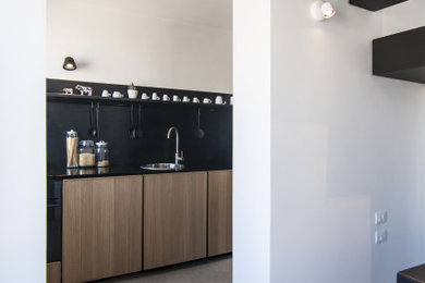Immagine di una cucina moderna con paraspruzzi nero, elettrodomestici da incasso, pavimento in cemento, pavimento beige e top nero