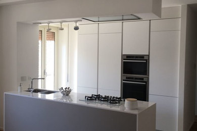 Esempio di una cucina moderna di medie dimensioni con lavello sottopiano, ante lisce, ante grigie, top in quarzo composito, elettrodomestici bianchi, parquet chiaro, pavimento marrone e top bianco
