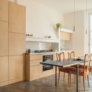 Esempio di una cucina design con ante lisce, ante in legno chiaro, paraspruzzi bianco, paraspruzzi con piastrelle diamantate, elettrodomestici neri, parquet scuro, nessuna isola, pavimento marrone e top bianco