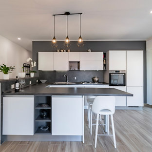 Ispirazione per una grande cucina contemporanea con lavello sottopiano, ante lisce, ante bianche, top in legno, paraspruzzi nero, paraspruzzi in gres porcellanato, elettrodomestici in acciaio inossidabile, pavimento in gres porcellanato, penisola, top nero e soffitto ribassato