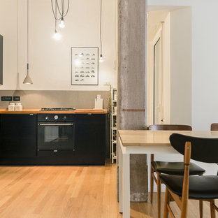 Immagine di una cucina scandinava di medie dimensioni con ante lisce, ante nere, top in legno, paraspruzzi grigio, paraspruzzi con piastrelle in ceramica, elettrodomestici neri, nessuna isola e parquet chiaro