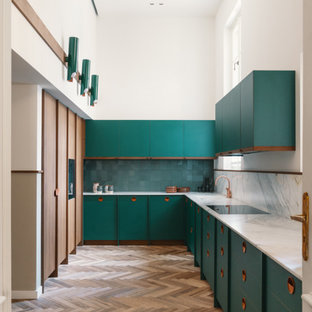 Foto di una grande cucina ad U minimal chiusa con lavello a vasca singola, ante lisce, ante verdi, paraspruzzi verde, elettrodomestici da incasso, nessuna isola, pavimento marrone e top bianco