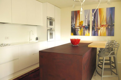 Idee per una cucina moderna di medie dimensioni con lavello integrato, ante a filo, ante bianche, top in superficie solida, paraspruzzi bianco, elettrodomestici bianchi, pavimento in cemento, pavimento beige e top bianco